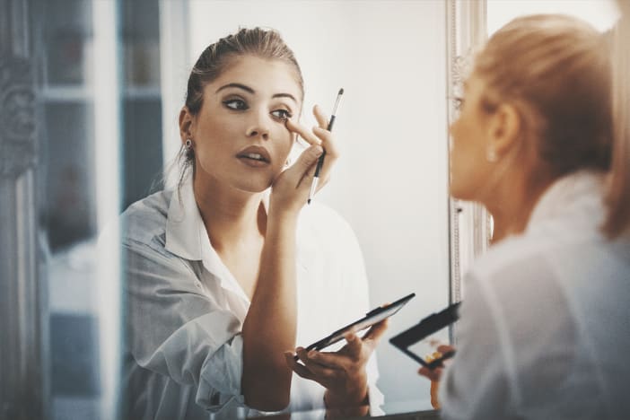 A woman applies makeup that has been insured with product liability insurance for beauty products.