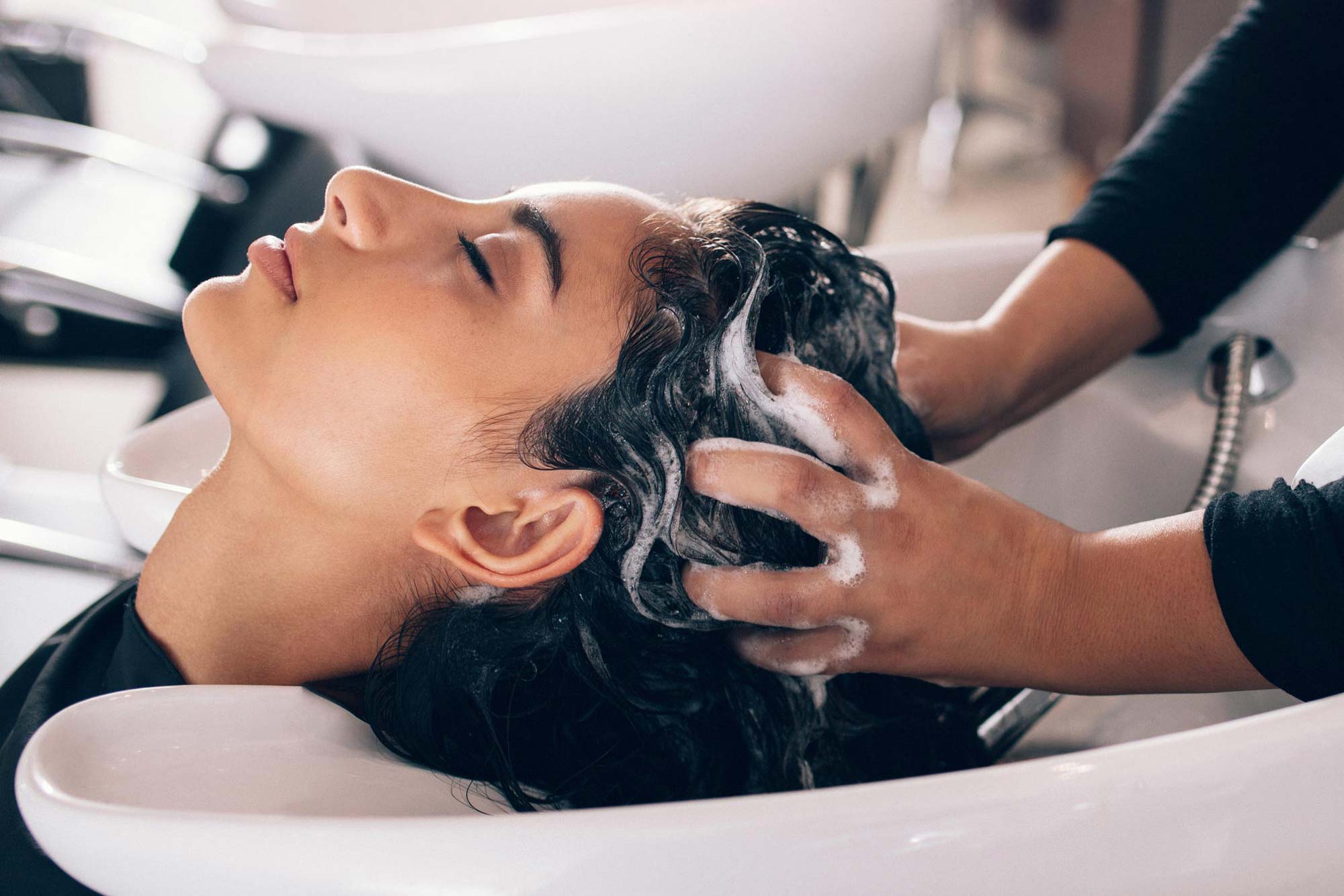 Hairstylist washing woman's hair