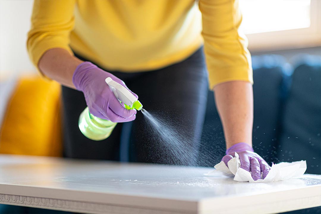 woman spraying cleaner on top of coffee table
