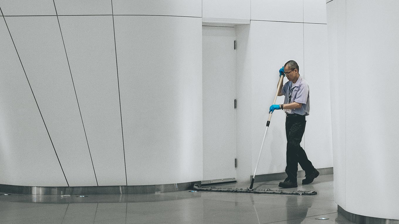 Picture of a janitor sweeping a hallway