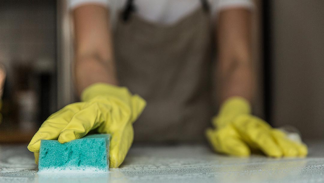 Person scrubbing countertop with a sponge