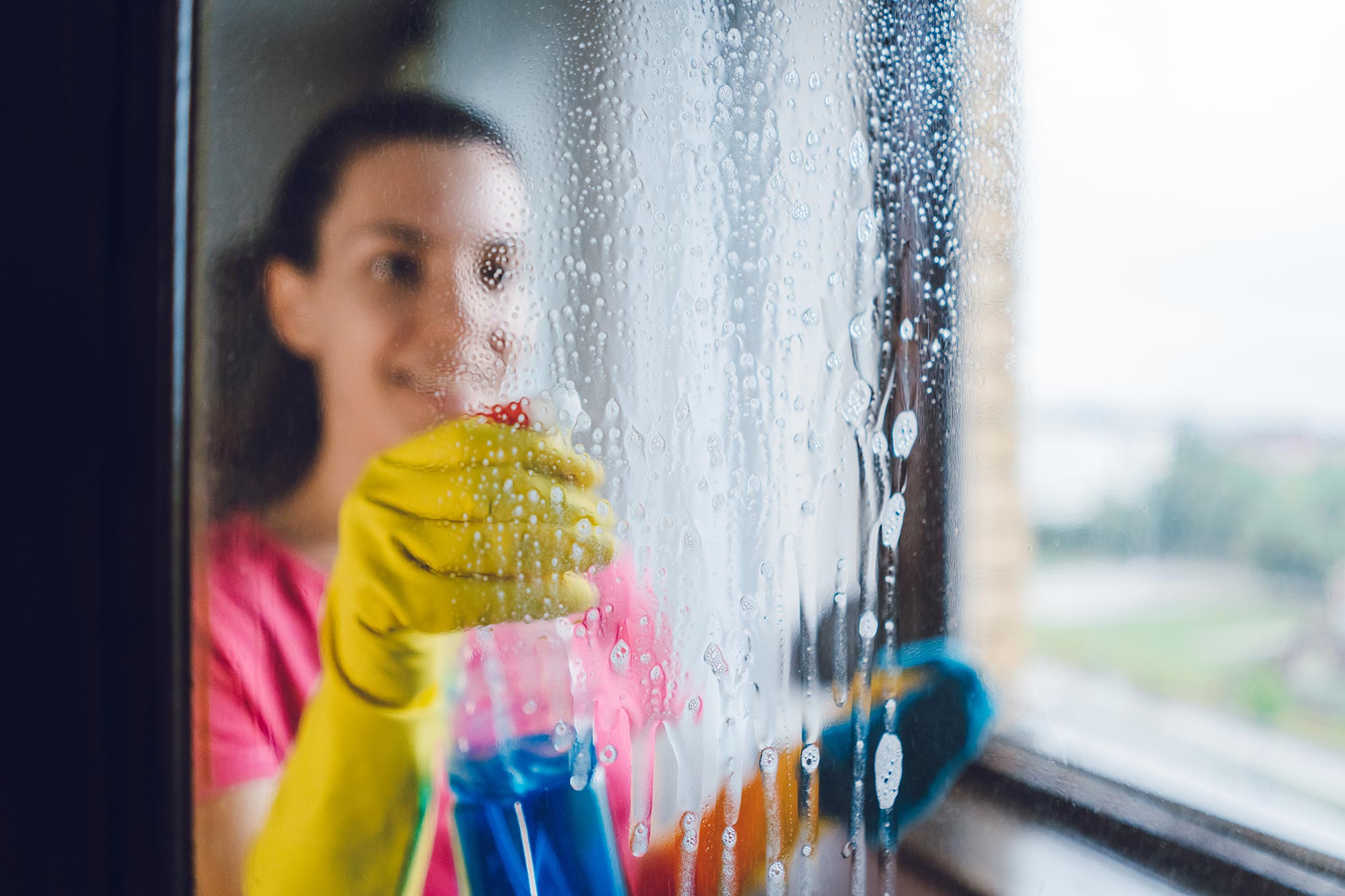 Woman spraying glass with window cleaner