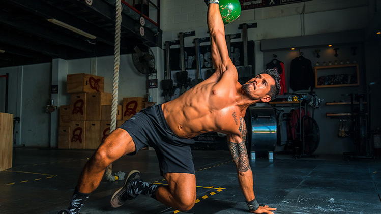 An athlete throws kettlebells from a half plank position. He can lead exercises with confidence because he's insured with crossfit trainer insurance.