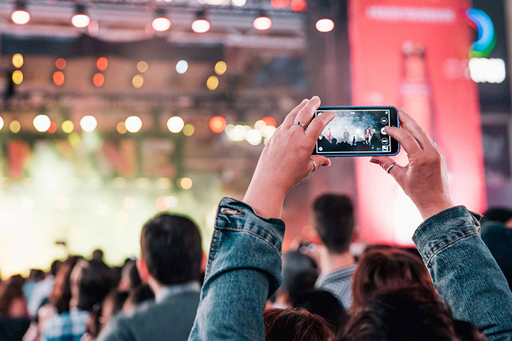 picture of a person taking a picture with her phone at a concert