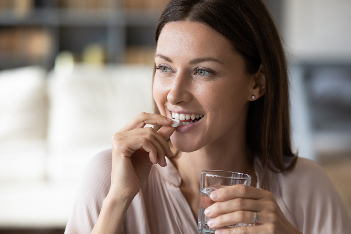 a woman takes an oral vitamin supplement.