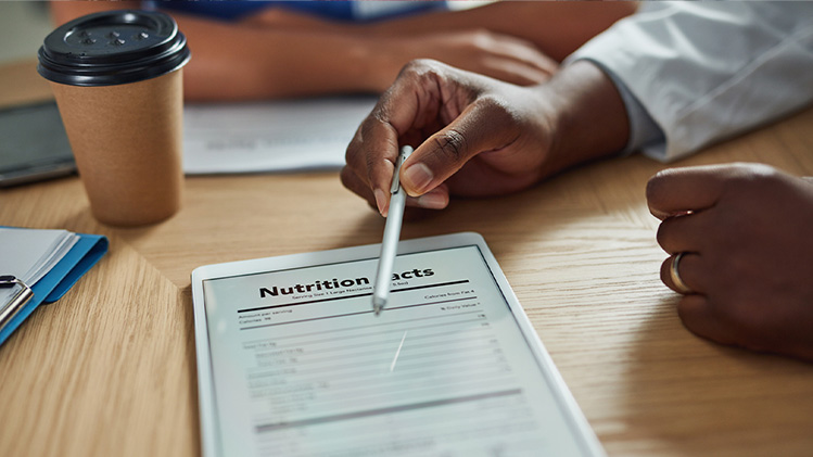 A insured nutritionist points out nutrition facts on a tablet. 