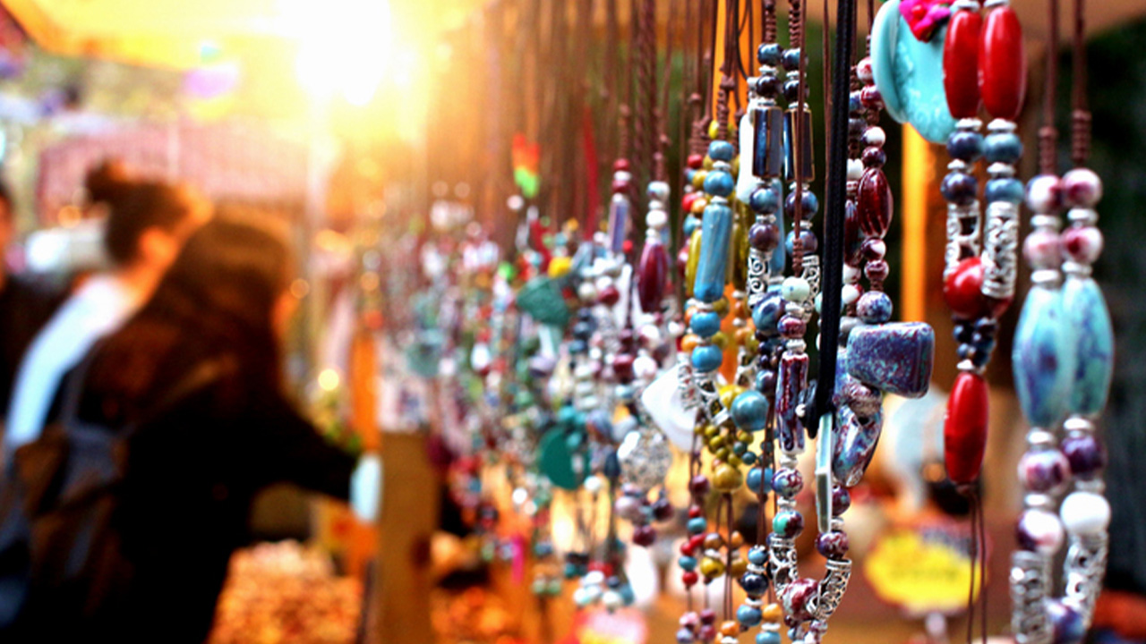 Beaded jewelry dangles from an art vendor's booth at sunset