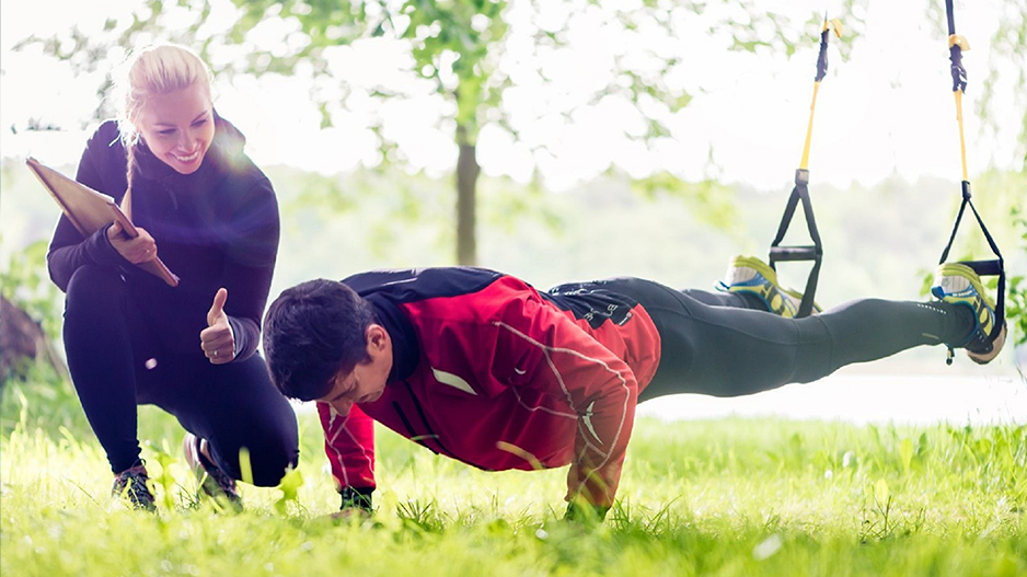 A trainer encourages a client who is doing pushups. The trainer can grow their business with personal trainer insurance.