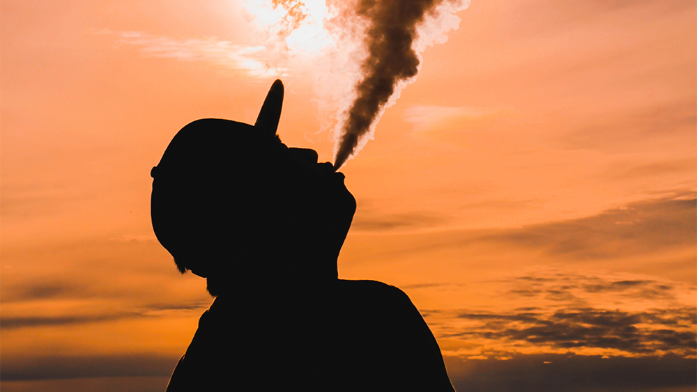 A silhouette blows vapor toward a sunsetting sky. the juice and products are protected with product liability insurance for vape products .