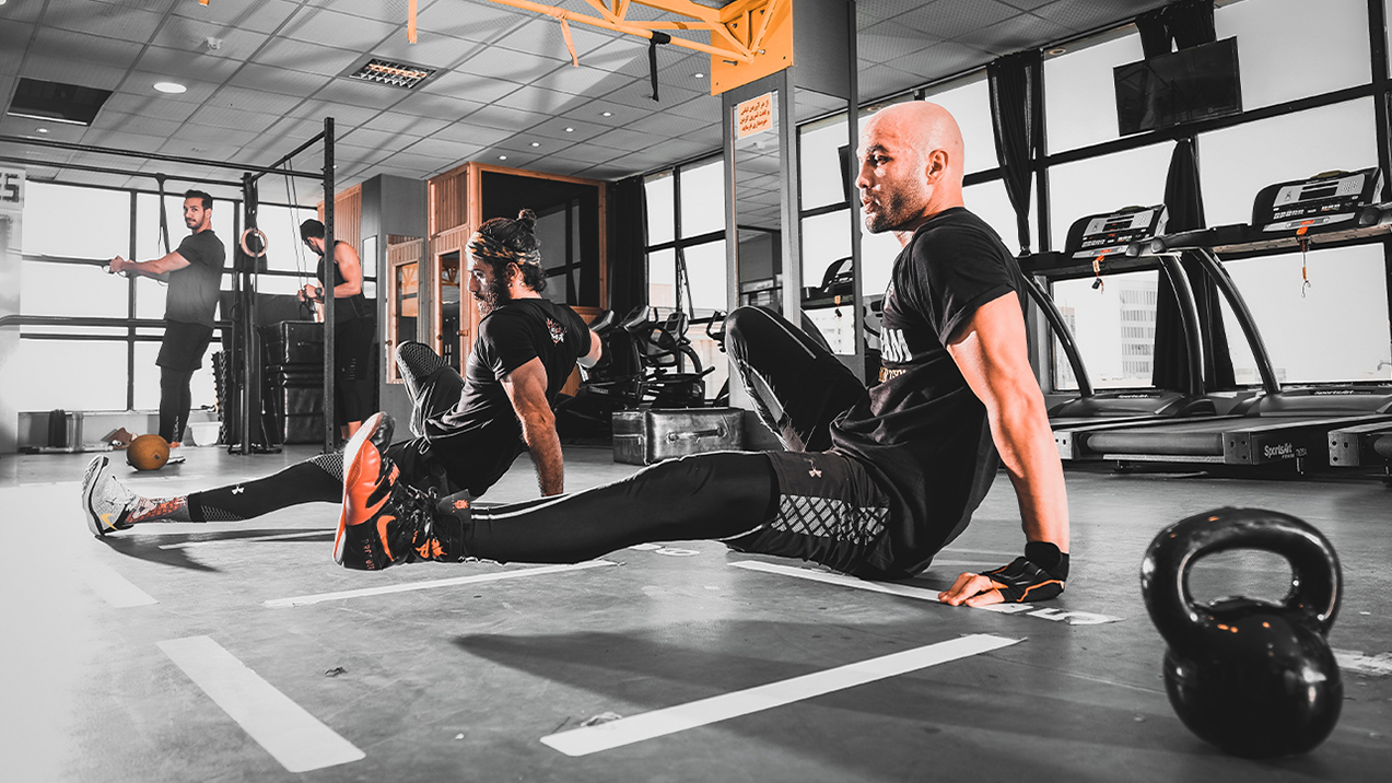A trainer exercises on the floor in a gym. He can focus on his workout with the knowledge that he has fitness instructor insurance.