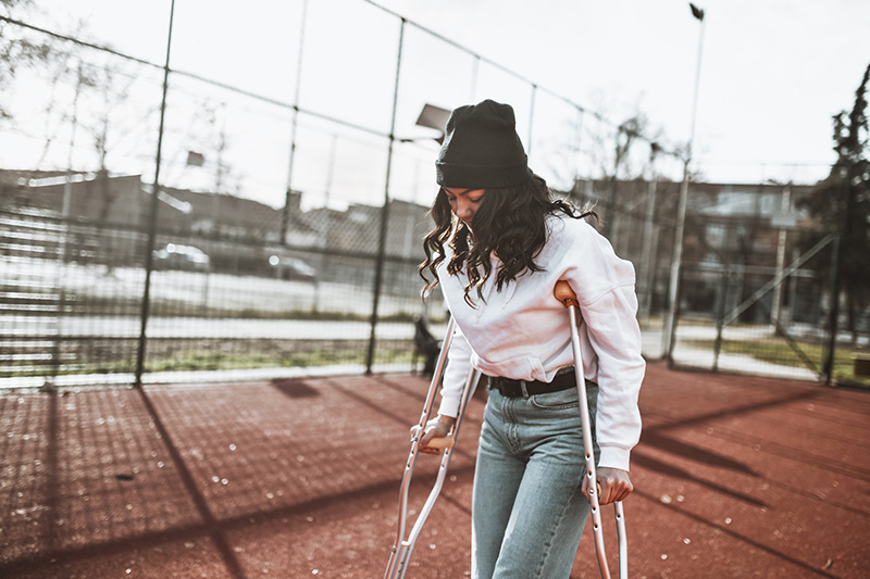 A young woman uses crutches.